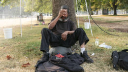 An unhoused man tries to stay cool near a misting station in Lents Park during an extreme heat wave in August 13, 2021, in Portland, Oregon.